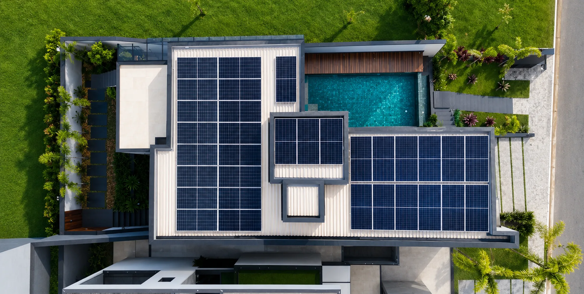 Vista superior de residência moderna com telhado tomado por painéis solares, ao lado de piscina e jardim
