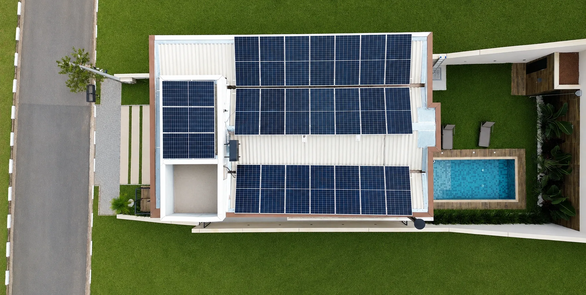 Vista superior de residência com três fileiras de painéis solares no telhado, com piscina e deck